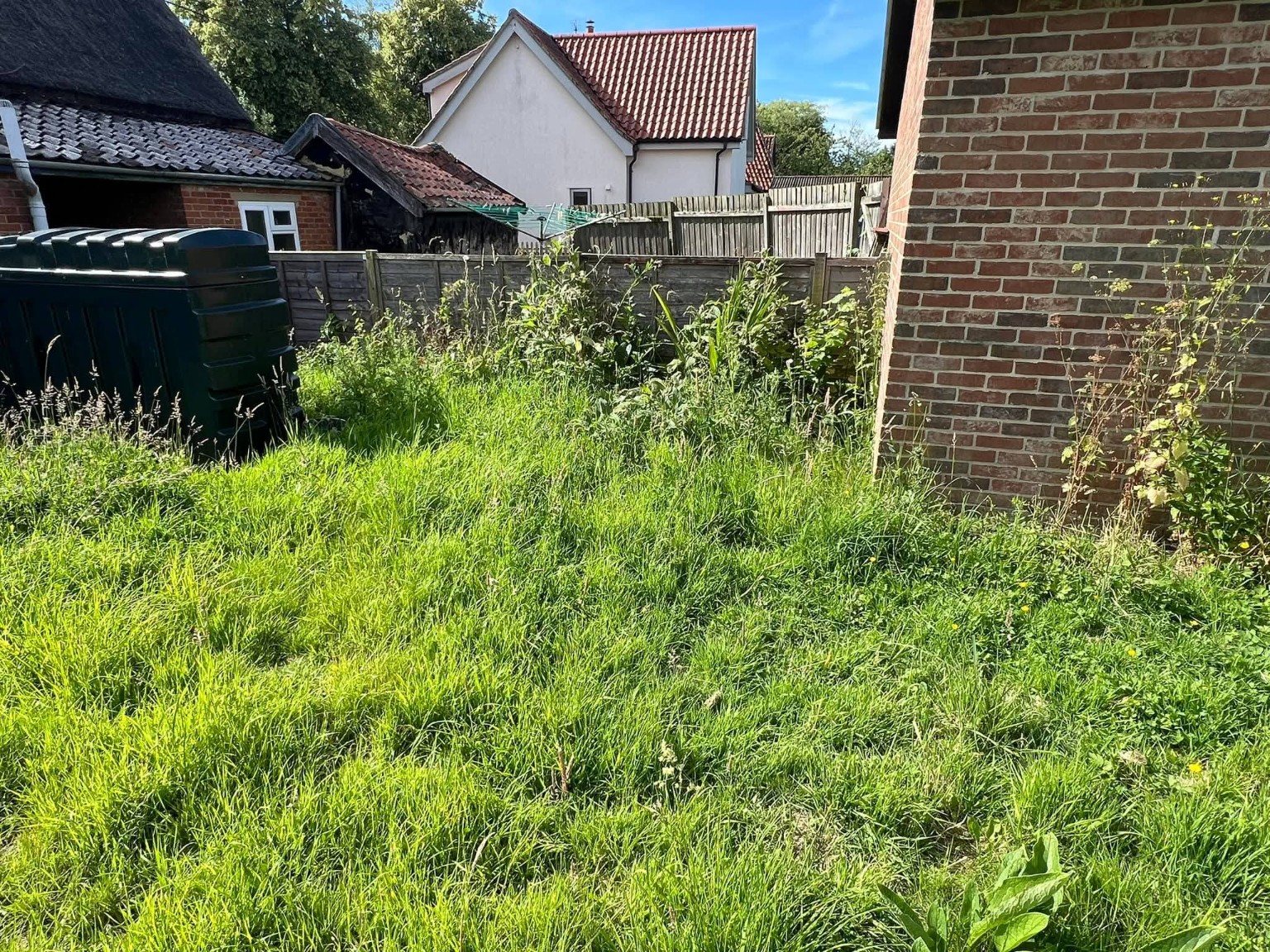 Long grass around the oil tank and outbuilding
