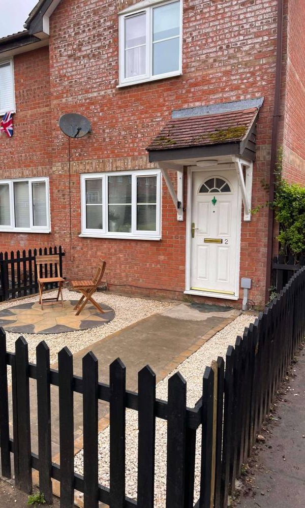 Finished front garden with gravel, a circular patio and a black picket fence